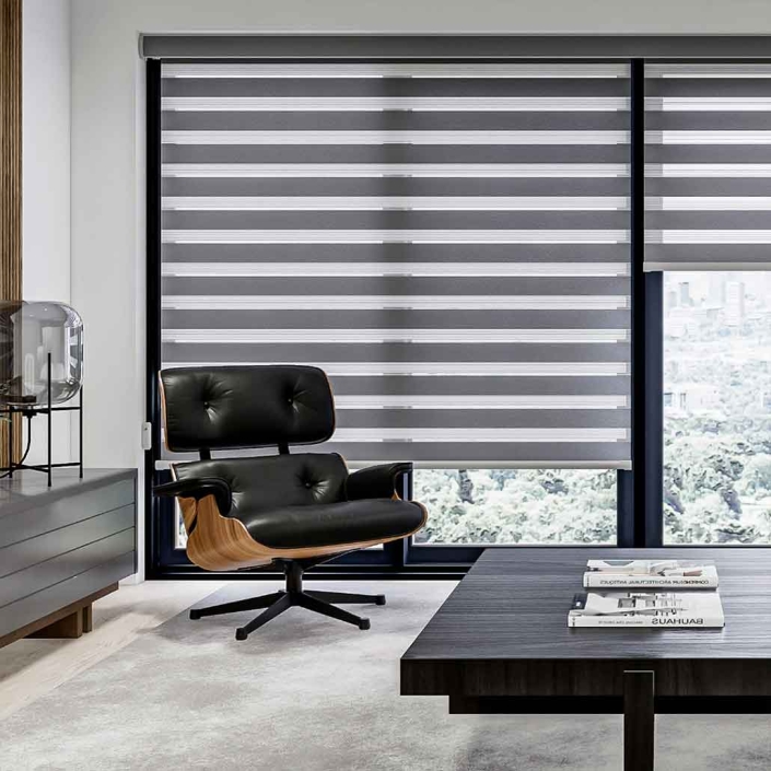 Cortinas modelo sheer elegance color gris colocadas en ventana de estudio con sillón individual moderno